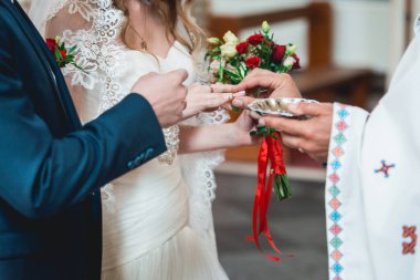 Rahip, düğün töreninde kilisede gelin ve damada altın alyansları takıyor. Geleneksel dini düğün töreni