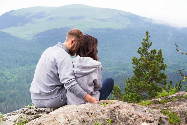 Liebende junge Hipster-Paar sitzt auf einem Berg, umarmt und l — Stockfoto