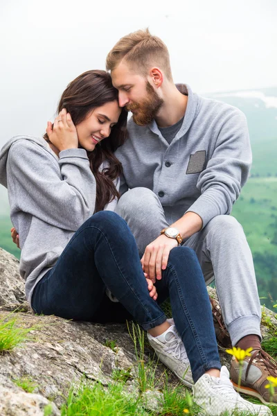 Glückliches junges verliebtes Paar auf einem Berg sitzend, sich umarmend und — Stockfoto