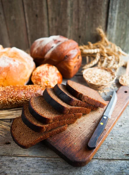 Sabroso pan fresco y trigo en la vieja mesa de madera — Foto de Stock