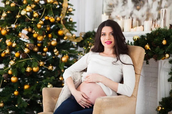 Mooie zwangere jongedame aanbrengen in een instelling van Kerstmis. — Stockfoto