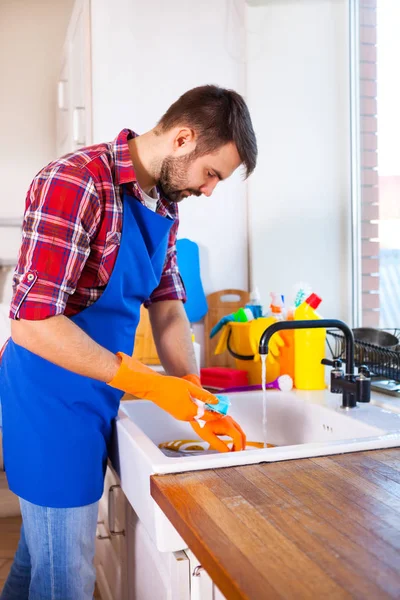 O homem faz a limpeza da cozinha. O jovem lava a louça. Cle... — Fotografia de Stock