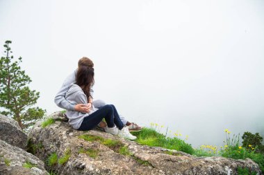 Mutlu genç çift aşık bir dağ üzerinde oturan sarılma ve lo