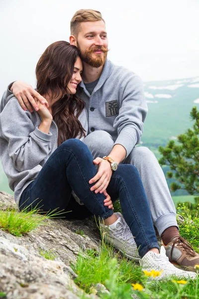 Glückliches junges verliebtes Paar auf einem Berg sitzend, sich umarmend und — Stockfoto