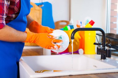 Adam mutfağın temizlik yapar. Genç adam bulaşıkları yıkar. Cle