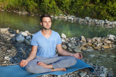 Adam dağ nehir kenarında meditasyon. Açık havada pratiği yoga