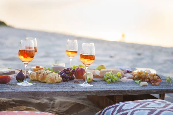 Piquenique na praia ao pôr do sol em estilo boho, comida e bebida conc — Fotografia de Stock