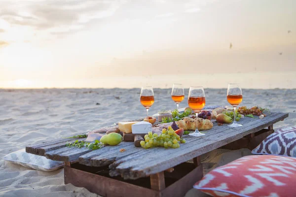 Piknik na plaży o zachodzie słońca w boho stylu, jedzenie i picie conc — Zdjęcie stockowe