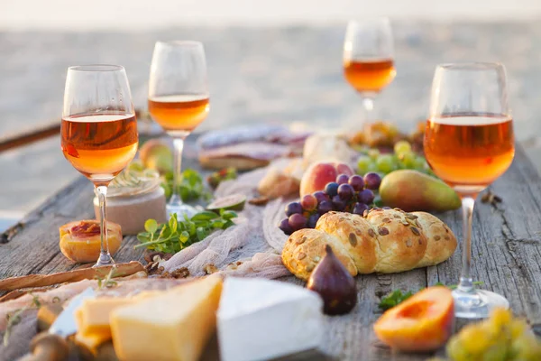 Piquenique na praia ao pôr do sol em estilo boho, comida e bebida conc — Fotografia de Stock