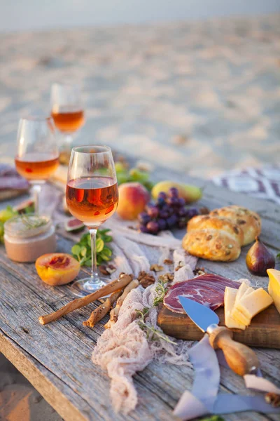 Picnic sulla spiaggia al tramonto in stile boho, cibo e bevande conc — Foto Stock