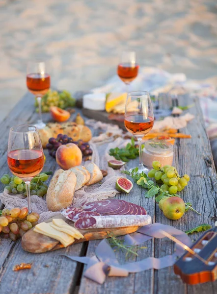 Piquenique na praia ao pôr do sol em estilo boho, comida e bebida conc — Fotografia de Stock