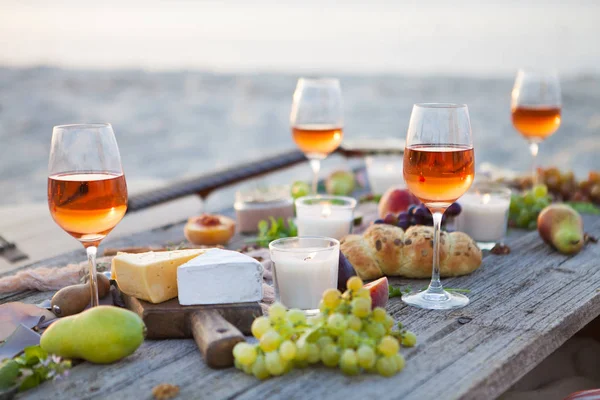 Piquenique na praia ao pôr do sol em estilo boho, comida e bebida conc — Fotografia de Stock