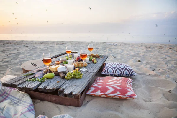 Piquenique na praia ao pôr do sol em estilo boho, comida e bebida conc — Fotografia de Stock