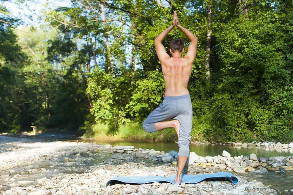 Hombre meditando cerca del río de la montaña. Yoga practicando al aire libre — Foto de Stock