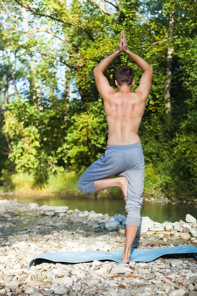 Hombre meditando cerca del río de la montaña. Yoga practicando al aire libre — Foto de Stock