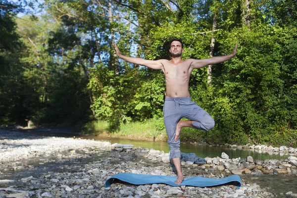 Hombre meditando cerca del río de la montaña. Yoga practicando al aire libre — Foto de Stock