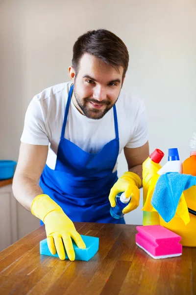 Zbliżenie, młody człowiek ubrany czyszczenia blatem kuchennym fartuch — Zdjęcie stockowe