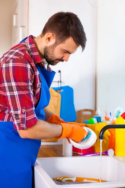 Man maakt het schoonmaken van de keuken. Jonge man wast de gerechten. Cle — Stockfoto