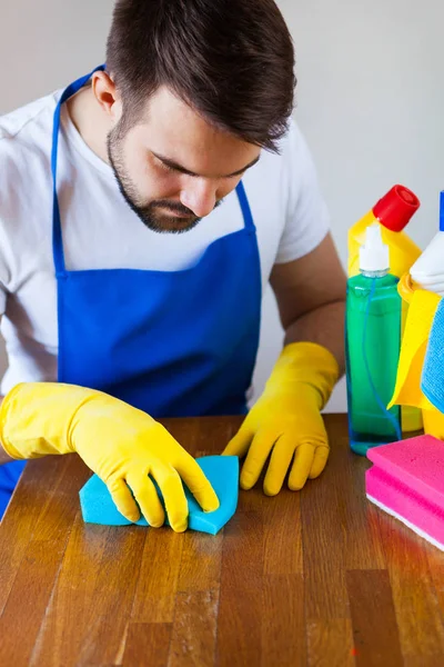 Nahaufnahme eines jungen Mannes mit Schürze, der Küchenarbeitsplatte putzt — Stockfoto