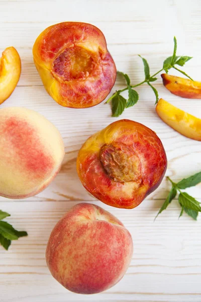 Fresh peaches with mint on wooden white background. Top view, fl — Stock Photo, Image