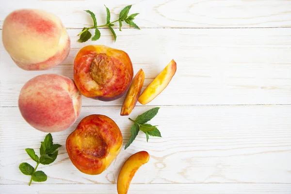 Fresh peaches with mint on wooden white background. Top view, fl — Stock Photo, Image