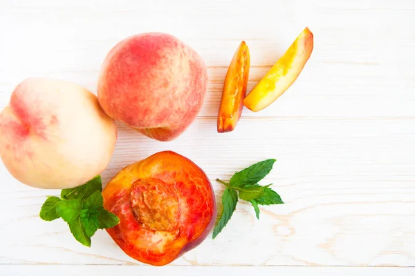 Fresh peaches with mint on wooden white background. Top view, fl — Stock Photo, Image