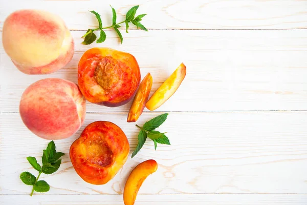 Fresh peaches with mint on wooden white background. Top view, fl — Stock Photo, Image