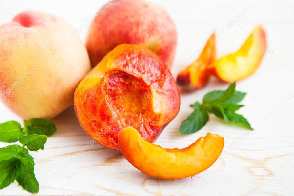 Fresh peaches with mint on wooden white background.