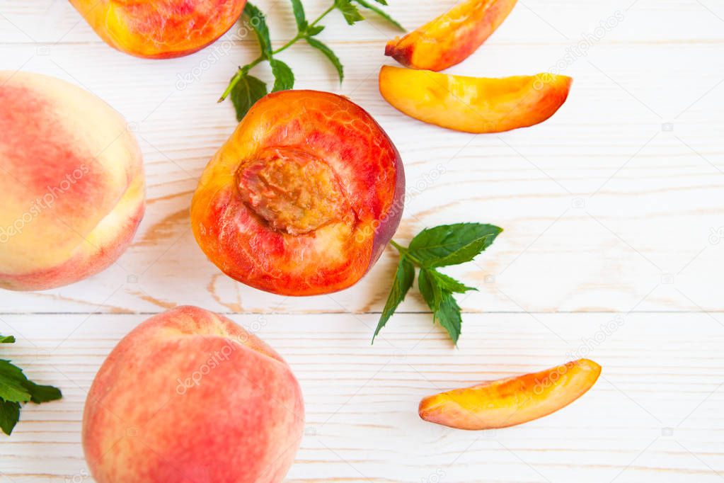 Fresh peaches with mint on wooden white background. Top view, fl