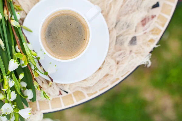 Bouquet Bunga lonceng musim semi putih dan cangkir kopi di atas meja di gar — Stok Foto