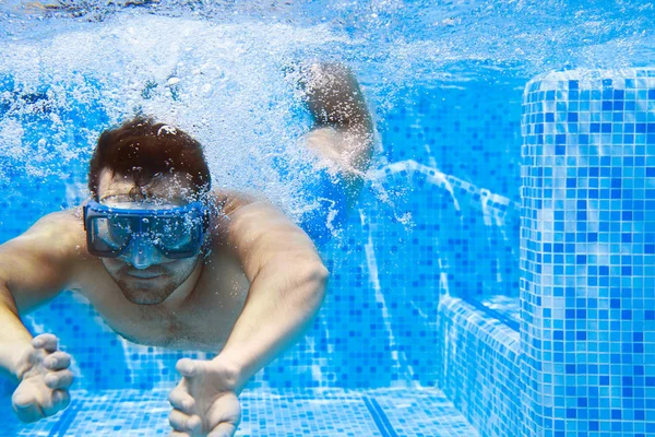 Young man in diving mask swimming the front crawl in a pool, tak