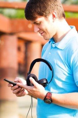 Yürüyüş ve müzik dinlemek için bir akıllı telefon kullanarak mutlu genç adam 