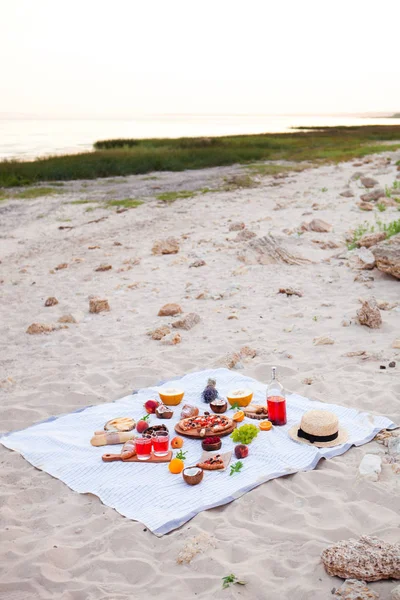 Picnic en la playa al atardecer en el cuadros blancos, comida y bebida — Foto de Stock