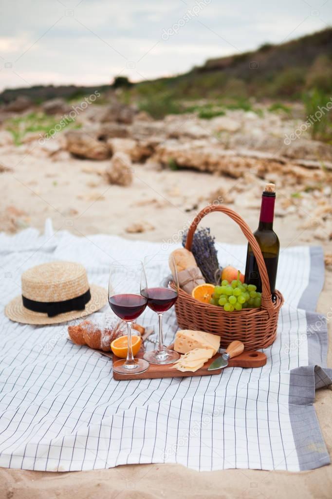 Picnic on the beach at sunset in the white plaid, food and drink
