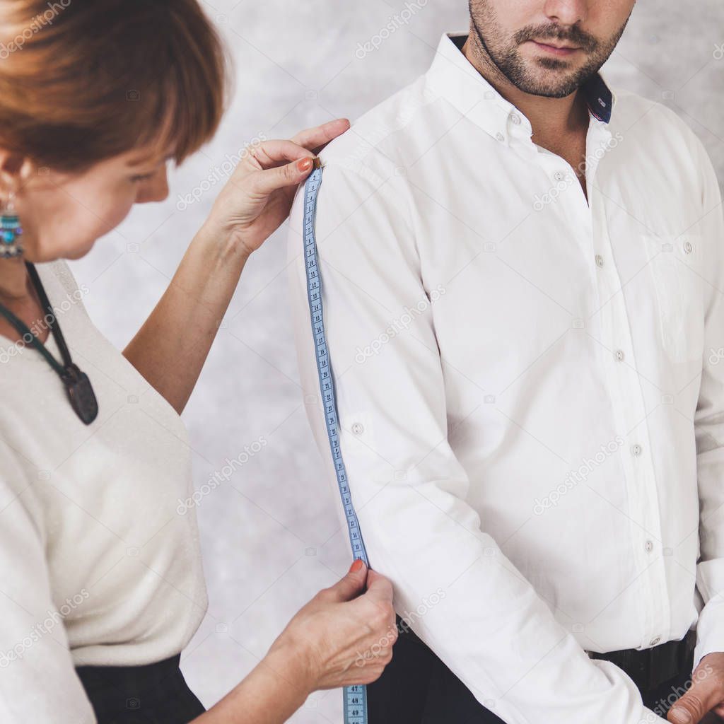 Woman tailor takes measures with male models. Fashion designer s