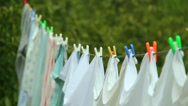 Чистая стиральная одежда висит на проволоке с колышком для одежды — стоковое видео