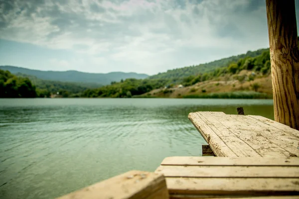 Προοπτική ξύλινη σανίδα άδειο τραπέζι μπροστά φύση θολή φόντο με το βουνό και στη λίμνη. — Φωτογραφία Αρχείου