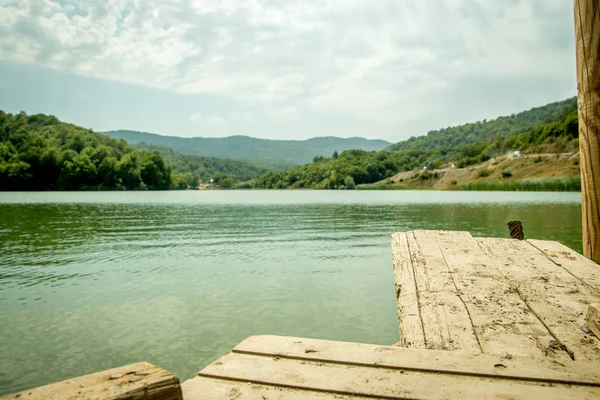 Προοπτική ξύλινη σανίδα άδειο τραπέζι μπροστά φύση θολή φόντο με το βουνό και στη λίμνη. — Φωτογραφία Αρχείου