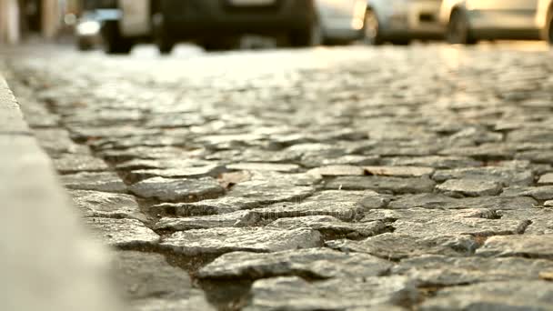 Close up van een oude geplaveide weg en auto's passeren in een afstand. Abstracte vintage straat achtergrond. — Stockvideo