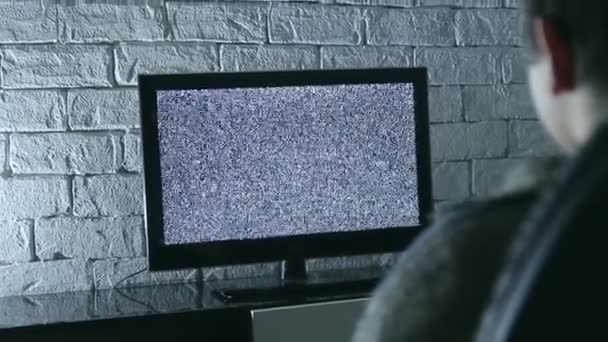 Kleiner Junge schaut LCD-Fernseher in einem dunklen Raum mit Ziegelwänden im Loft-Stil, Rückansicht. — Stockvideo