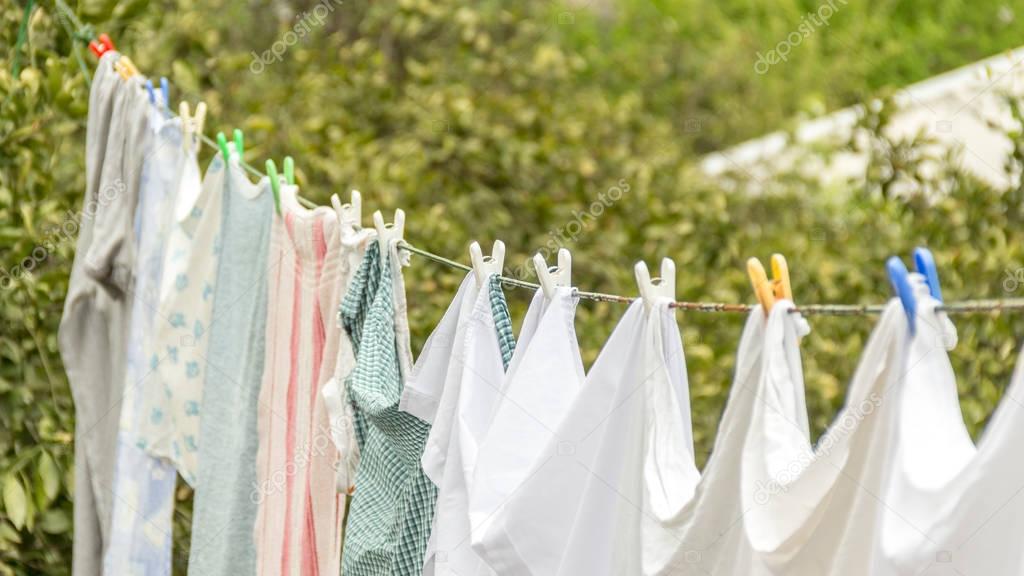 Laundry line with white clothes and green nature background.
