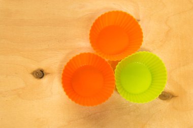 Turuncu ve hafif yeşil silikon fincan kek veya katı ahşap zemin üzerine kek pişirme. Üstten Görünüm.