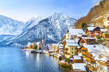 Kış aylarında mavi gökyüzü ve bulutlar ile güzel bir soğuk güneşli günde geleneksel yolcu gemisi ile Alpler 'de ünlü Hallstatt Lakeside kasaba klasik kartpostal görünümü, Salzkammergut bölgesi, Avusturya