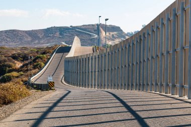 Uzak tepelere doğru uzanan uluslararası sınır duvar arasında San Diego ve Tijuana