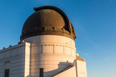 Los Angeles, California - 19 Kasım 2017: Zeiss 12-inç refracting teleskop konut dome yakınındaki Griffith Gözlemevi, üstüne batımında Hollywood hills insanlar görünümü.