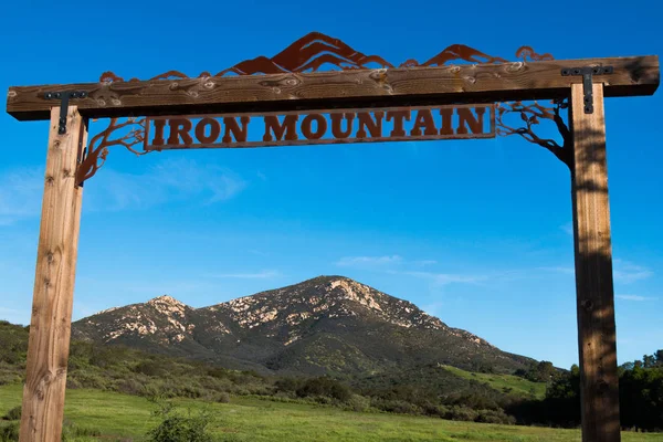 POWAY, CALIFORNIA - MARCH 16, 2017:  Close-up of the signage at the entrance to the Iron Mountain trail, and a view of Iron Mountain in the background, the second highest peak in the city of Poway.