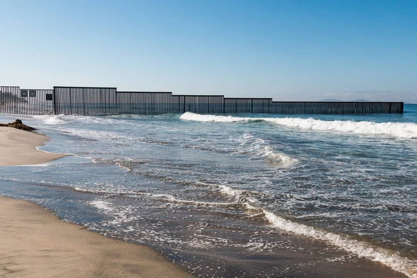 The western end of the international border wall in the Pacific ocean, as it separates San Diego, California and Tijuana, Mexico.
