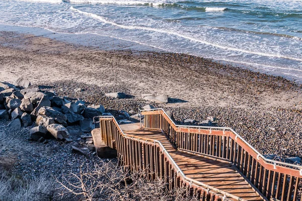 A staircase leading down to a stone-covered beach at South Carlsbad State Beach in San Diego, California.