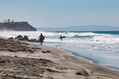 Encinitas, California/ABD - 4 Ekim 2016: İki erkek sörfçü dışarı baş Encinitas, Kaliforniya'da Beacon'ın plajda sörf tahtaları taşıyan denize.