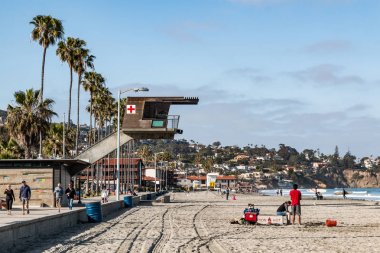 La Jolla, Kaliforniya/ABD - 28 Nisan 2018: İnsanlar güneşli bir La Jolla Shores kumsalda engelsiz görünümlerde sağlamak için plaj üzerinde gezinen modern cankurtaran istasyonu yakınında tadını çıkarın.    